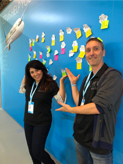 Veronica Jowers (left) and Kim Wens (right) standing in front of the wall with posted questions and answers at Ignite '19 Europe.